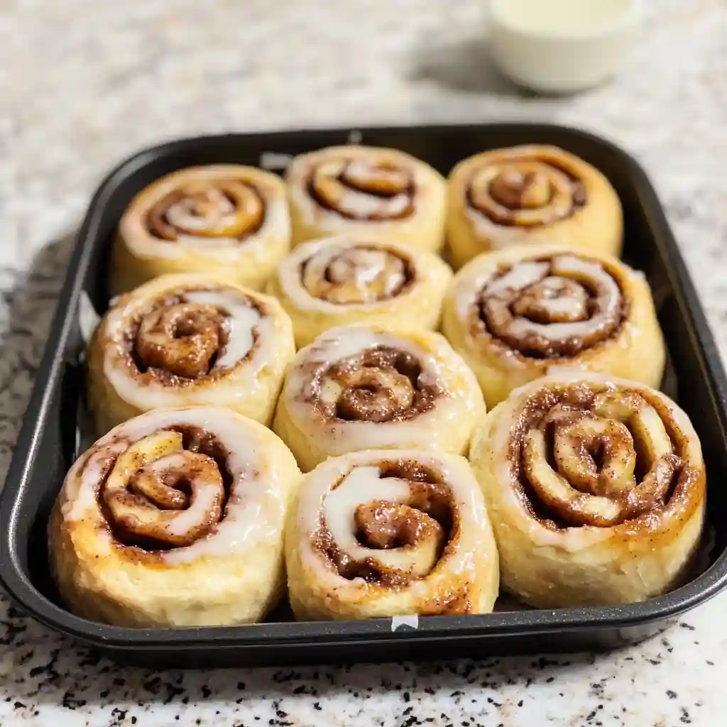 Tray of homemade cinnamon rolls topped with icing glaze.