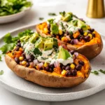 Baked sweet potatoes filled with black beans, corn, avocado, onions, and creamy yogurt sauce