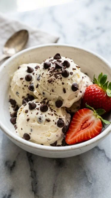 Bowl of creamy almond milk ice cream topped with almonds and chocolate drizzle
