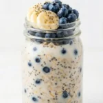 Blueberry Chia Overnight Oats in a glass jar with fresh berries on top