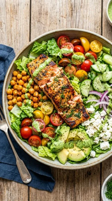 Salmon and avocado salad served in a bowl, garnished with fresh vegetables