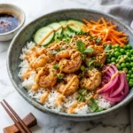 Shrimp rice bowls topped with spicy mayo served in a colorful bowl.