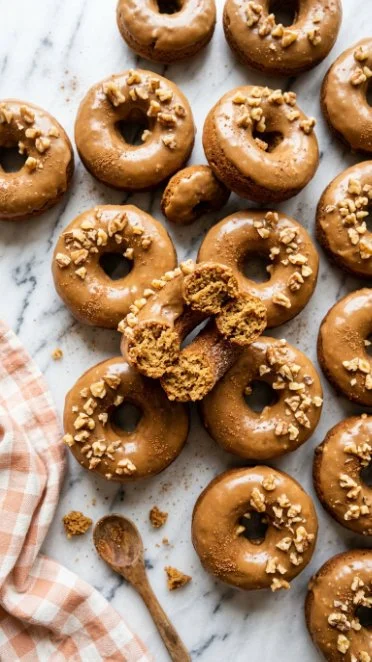 Baked pumpkin donuts with brown sugar icing on a rustic table