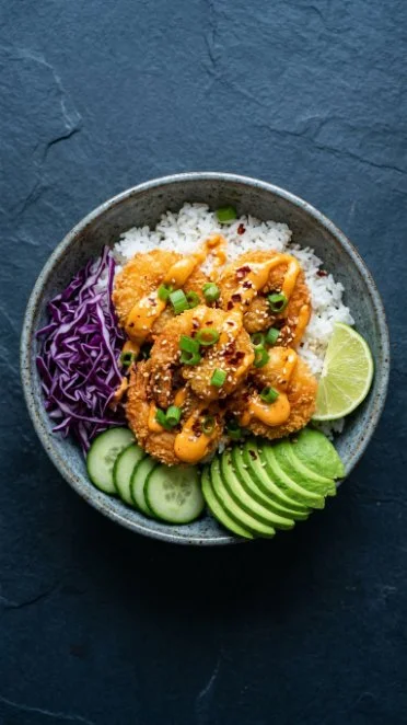 Crispy and creamy Bang Bang Shrimp Rice Bowl topped with greens and sauce