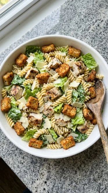 Easy Chicken Caesar Pasta Salad in a bowl with Caesar dressing and toppings.