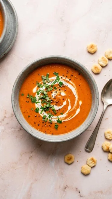 Bowl of creamy roasted tomato soup garnished with fresh basil and croutons