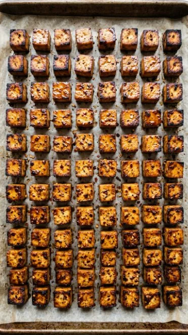 Plate of spicy roasted tofu garnished with fresh herbs and spices.
